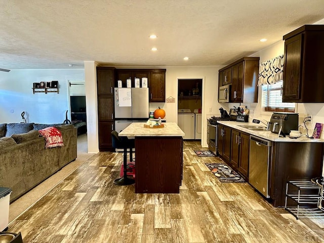 kitchen with a center island, a breakfast bar, washing machine and clothes dryer, stainless steel appliances, and light countertops