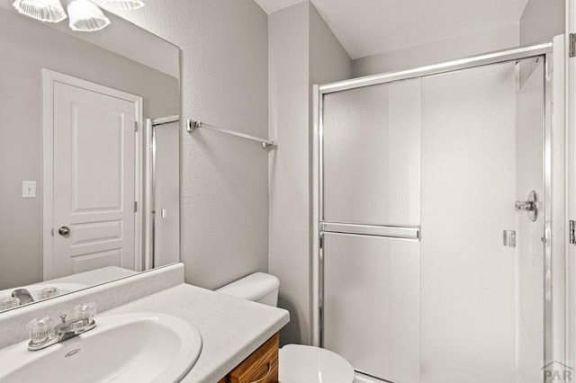 bathroom featuring toilet, a textured wall, a shower stall, and vanity