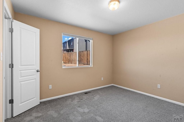 spare room with carpet floors, visible vents, and baseboards