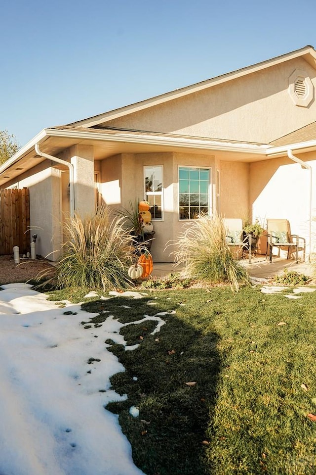 exterior space with a patio area, fence, a front lawn, and stucco siding