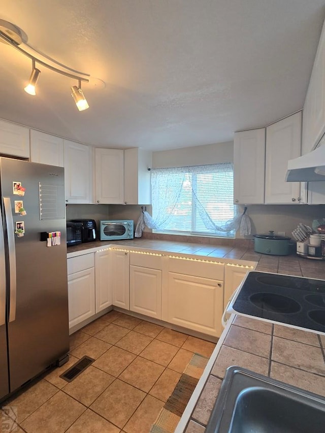 2631 Norwich Ave, Pueblo, CO 81003 - kitchen featuring freestanding refrigerator, tile countertops, white cabinets, and light tile patterned floors