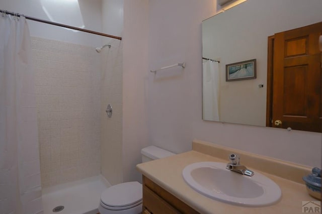 full bath with a tile shower, vanity, and toilet