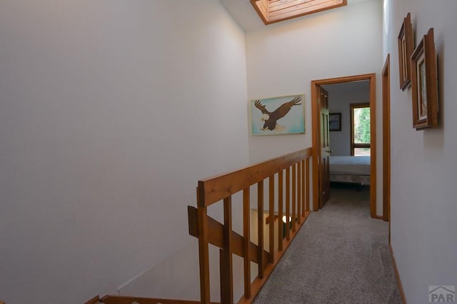 hallway featuring a skylight, light carpet, and baseboards