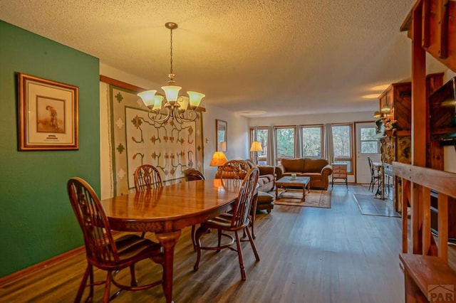 dining area featuring a textured ceiling, a chandelier, and dark wood-type flooring