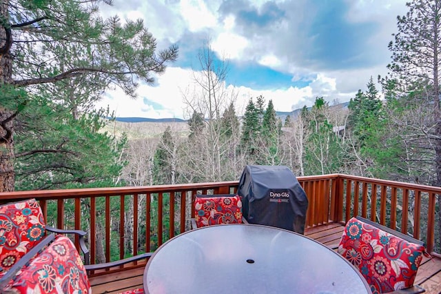 wooden terrace featuring a forest view, a mountain view, outdoor dining area, and area for grilling