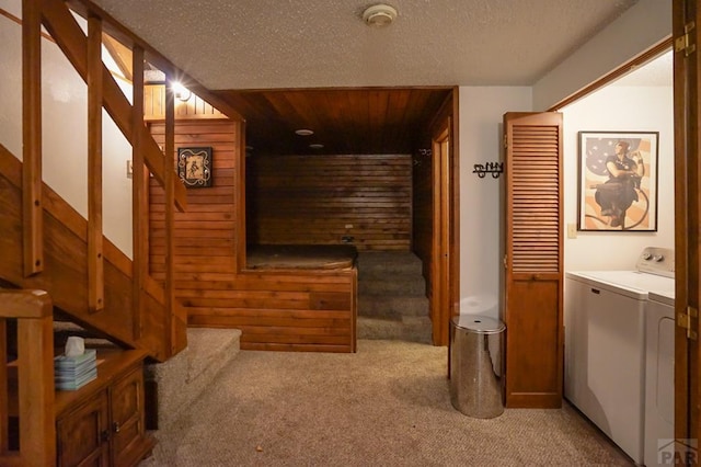 corridor with stairway, light carpet, wooden walls, a textured ceiling, and washer / dryer