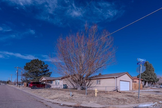 ranch-style house featuring an attached garage and fence