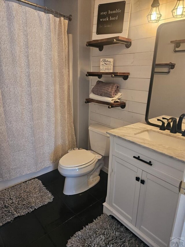 full bath with toilet, tile patterned floors, curtained shower, and vanity