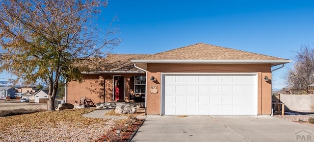 ranch-style home with driveway, an attached garage, and stucco siding