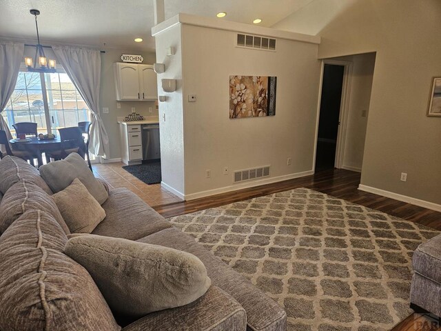 living room featuring visible vents, a notable chandelier, light wood-style flooring, and baseboards