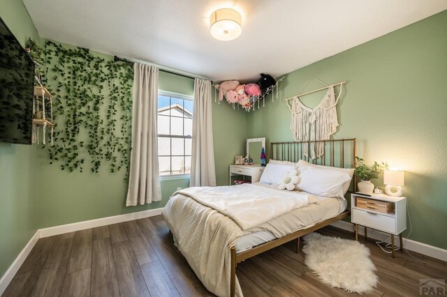 bedroom with dark wood-type flooring and baseboards