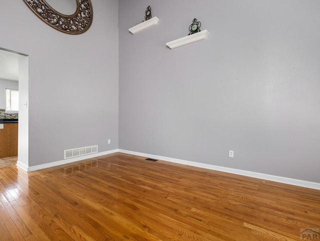 spare room featuring baseboards, visible vents, and wood finished floors