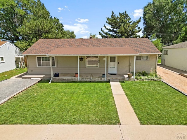 ranch-style house featuring a front yard, covered porch, and roof with shingles