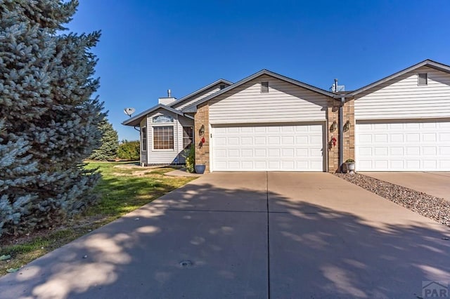 view of front of property featuring a garage, brick siding, and driveway