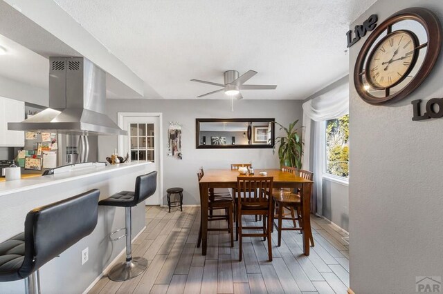 dining room with light wood-type flooring, a ceiling fan, and baseboards