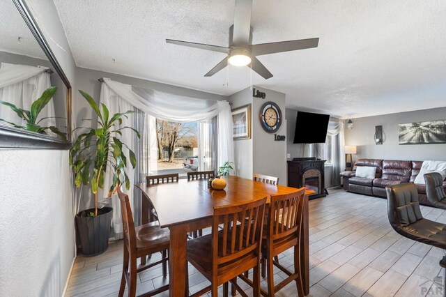 dining area with a textured ceiling, ceiling fan, and light wood-type flooring