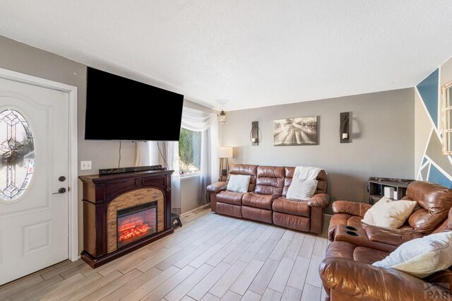 living room featuring light wood-type flooring and a glass covered fireplace