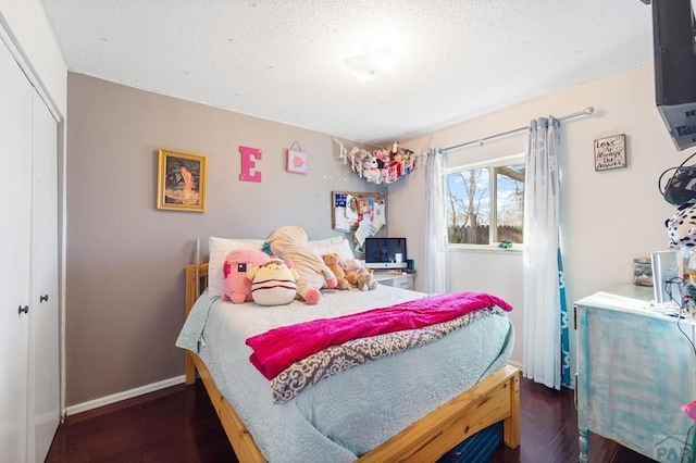 bedroom with a textured ceiling, a closet, baseboards, and dark wood-type flooring