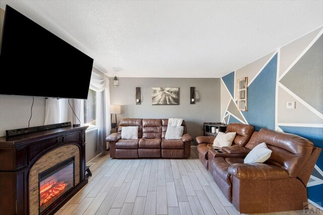 living room with light wood-style floors and a glass covered fireplace