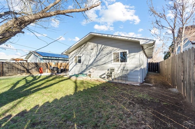 rear view of property featuring a fenced backyard and a yard