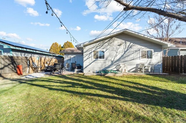 rear view of house featuring fence private yard, a patio area, and a lawn