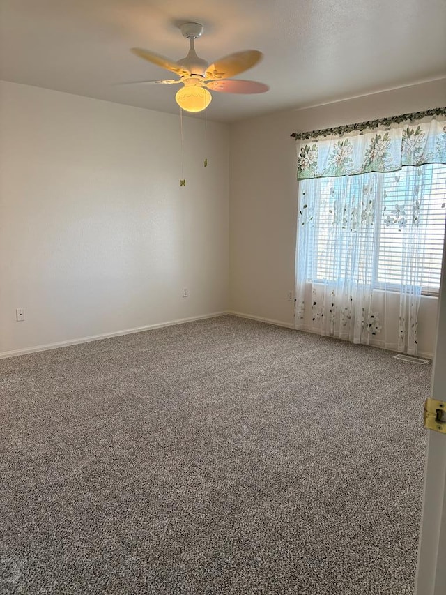 carpeted empty room with a ceiling fan and baseboards