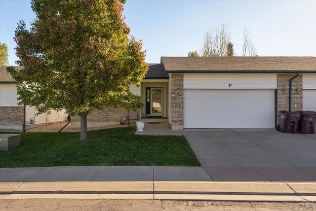 view of front facade with a garage, driveway, brick siding, and a front lawn