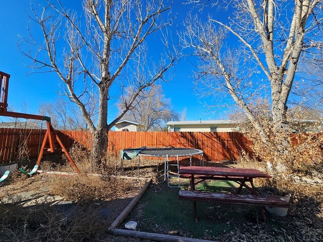 view of yard featuring a fenced backyard, a trampoline, and a playground