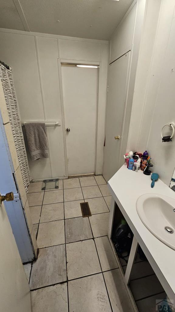 bathroom with a textured ceiling, a sink, and tile patterned floors