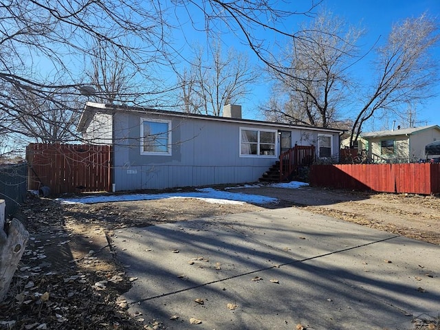 view of front facade with driveway, a chimney, and fence