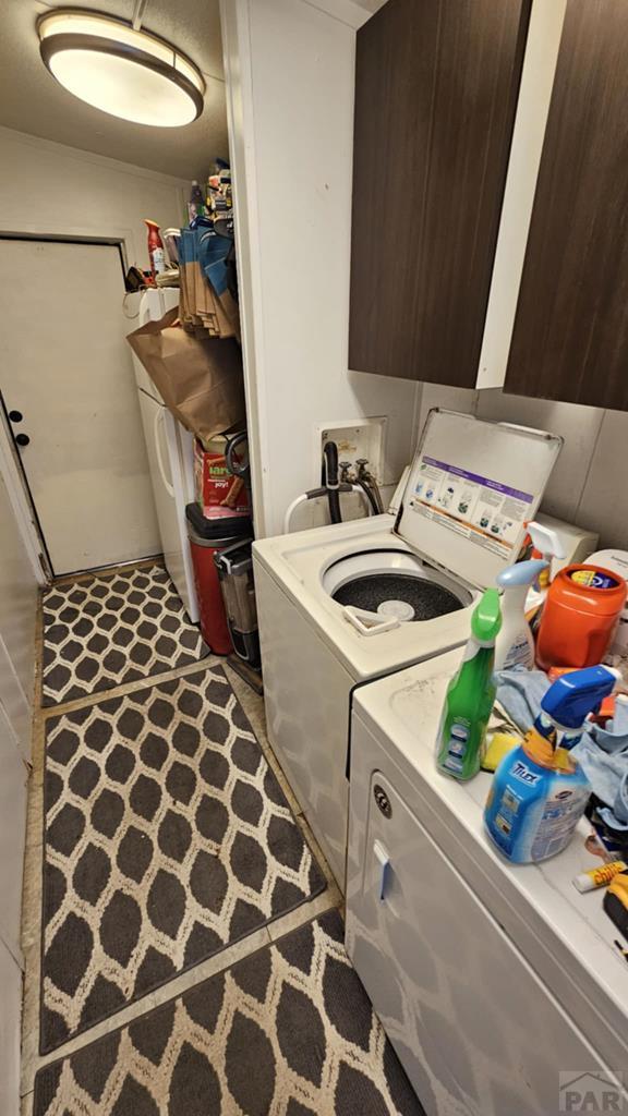 clothes washing area with washing machine and dryer and cabinet space