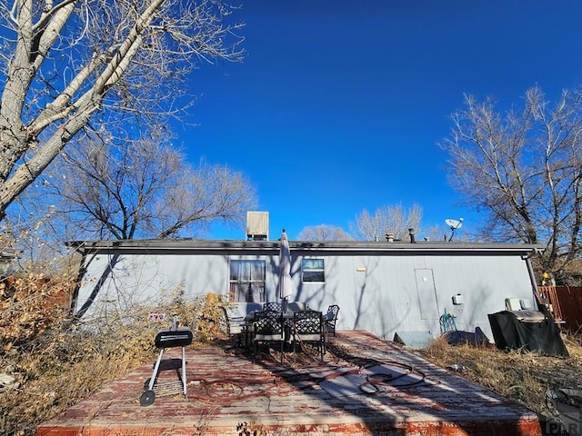 rear view of property with outdoor dining area and a wooden deck