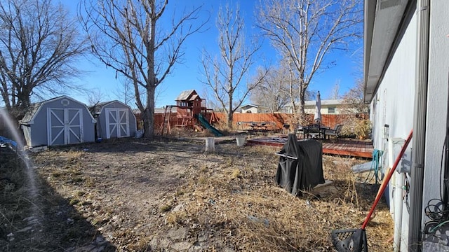 view of yard featuring an outbuilding, a shed, a playground, and a fenced backyard