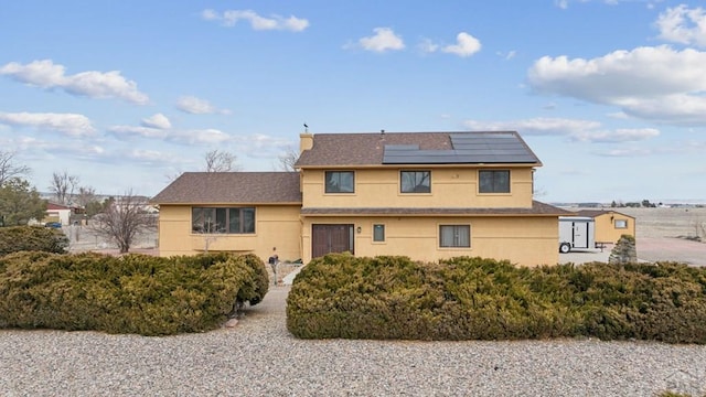 view of front of house with stucco siding and roof mounted solar panels