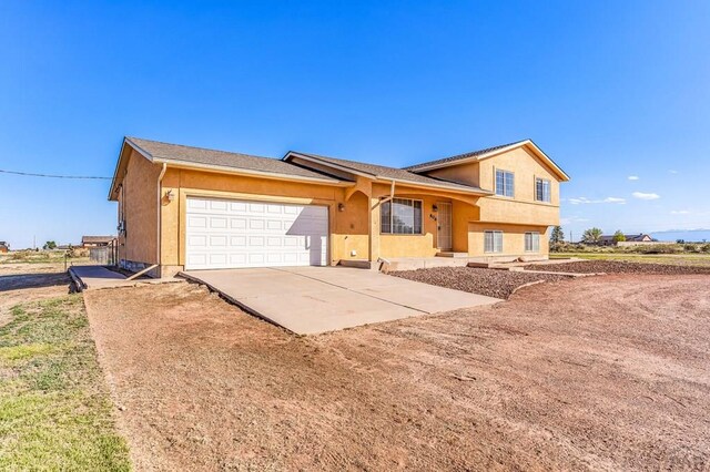 806 N Monarch Dr, Pueblo, CO 81007 - split level home with concrete driveway, an attached garage, and stucco siding