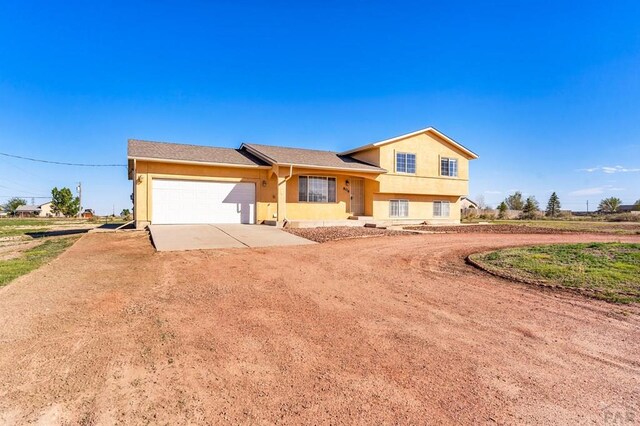 806 N Monarch Dr, Pueblo, CO 81007 - tri-level home with concrete driveway, a garage, and stucco siding