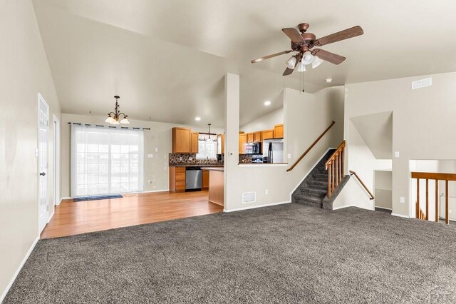 806 N Monarch Dr, Pueblo, CO 81007 - unfurnished living room with light carpet, vaulted ceiling, a chandelier, a ceiling fan, and baseboards