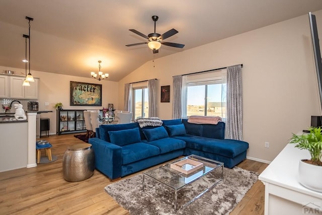 living room with light wood-type flooring, vaulted ceiling, baseboards, and ceiling fan with notable chandelier