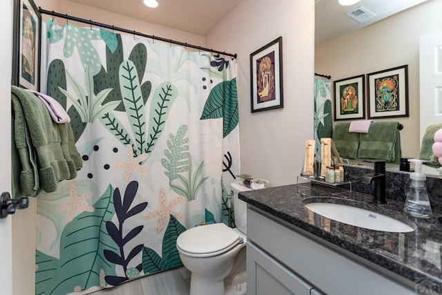 full bathroom featuring toilet, wood finished floors, vanity, and visible vents