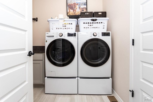 washroom with visible vents, cabinet space, and washer and dryer