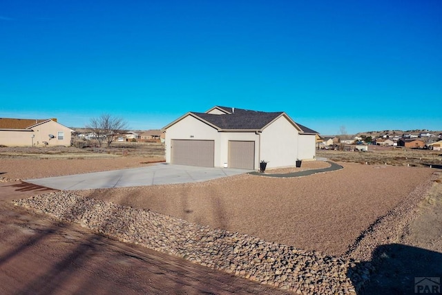 view of side of property with a residential view, concrete driveway, an attached garage, and stucco siding