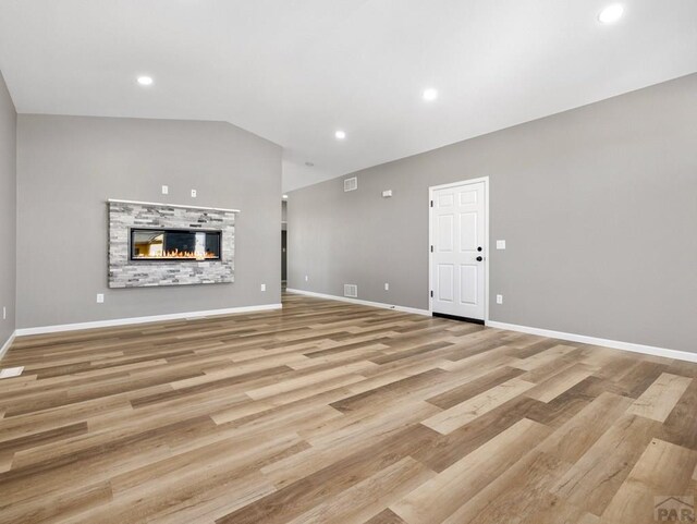 unfurnished living room with recessed lighting, baseboards, vaulted ceiling, and light wood finished floors