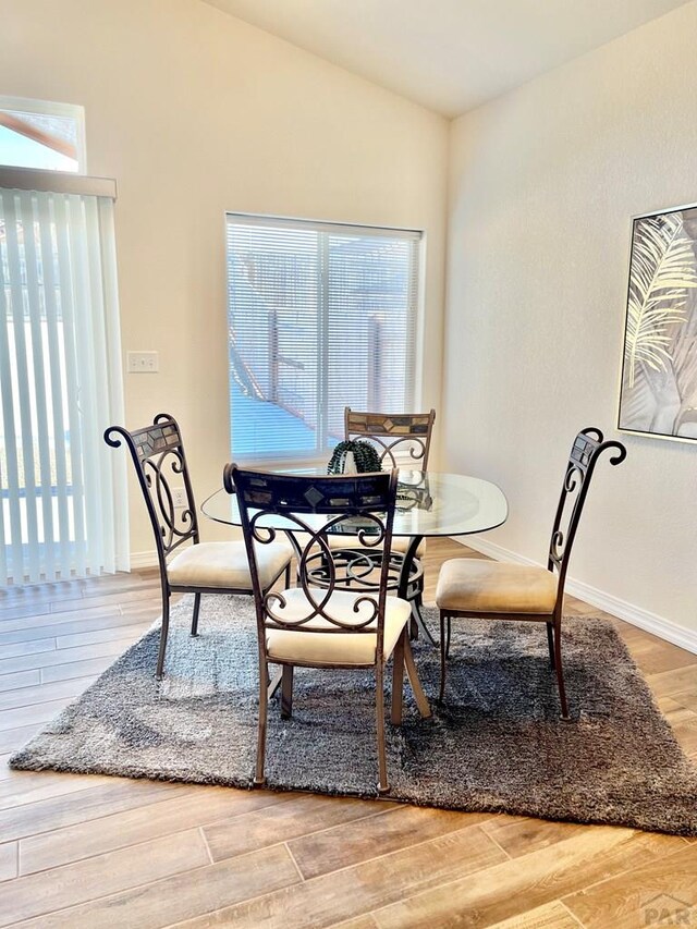 dining space with lofted ceiling, wood finished floors, and baseboards