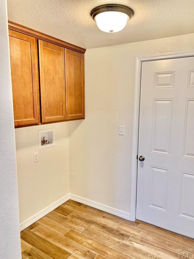 laundry room with hookup for a washing machine, baseboards, cabinet space, and light wood finished floors