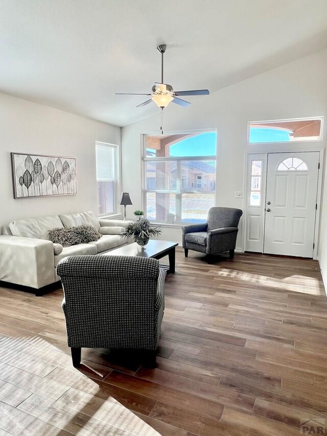 living area with ceiling fan, vaulted ceiling, and wood finished floors