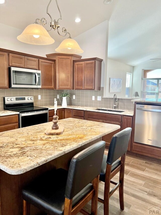 kitchen featuring appliances with stainless steel finishes, a sink, a breakfast bar, and pendant lighting