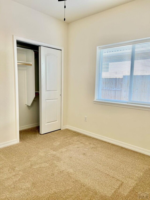 unfurnished bedroom with light carpet, baseboards, and a closet