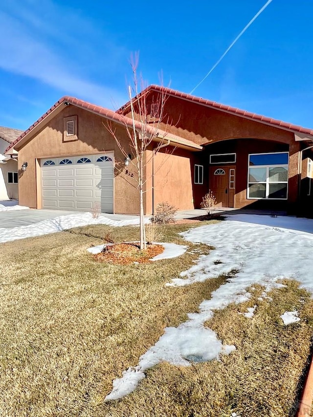 single story home featuring a front yard, an attached garage, and stucco siding