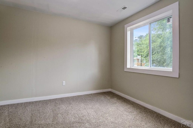 empty room featuring visible vents, carpet floors, and baseboards