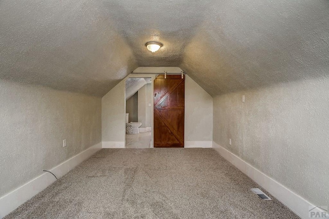 bonus room with visible vents, a textured ceiling, baseboards, carpet flooring, and lofted ceiling